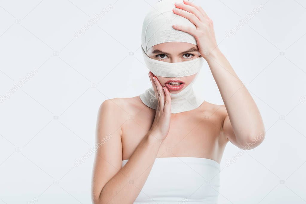 woman with bandages after plastic surgery touching head isolated on white