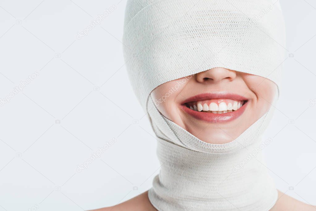 close up of woman face with white bandages and smile isolated on white