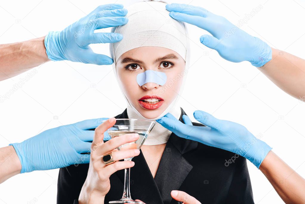 hands in gloves touching woman with bandages after plastic surgery and cocktail isolated on white