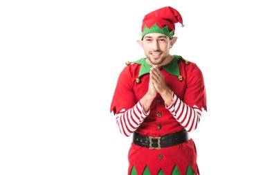 smiling man in christmas elf costume looking at camera and rubbing hands in anticipation isolated on white clipart