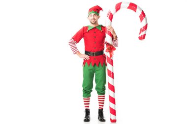 Noel elf kostümü büyük şeker ayakta kalça üzerinde el ile kamışı izole üzerinde beyaz adam gülümseyen