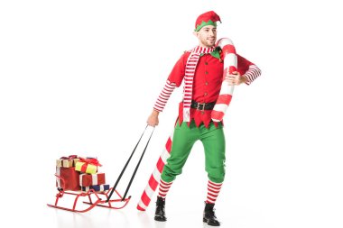mutlu Noel elf kostümü ile kızak taşıyan erkekte sunar ve büyük şeker kamışı beyaz izole