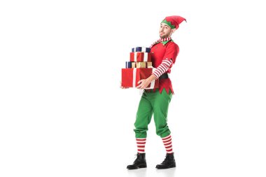 adam kameraya bakarak ve yığın üzerinde beyaz izole hediye taşıyan Noel elf kostümü