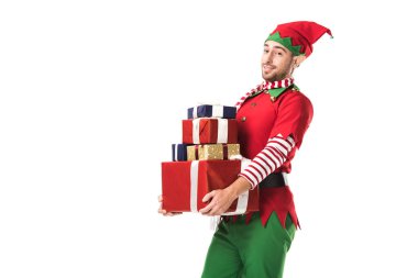 adam kameraya bakarak ve yığın üzerinde beyaz izole hediye taşıyan Noel elf kostümü
