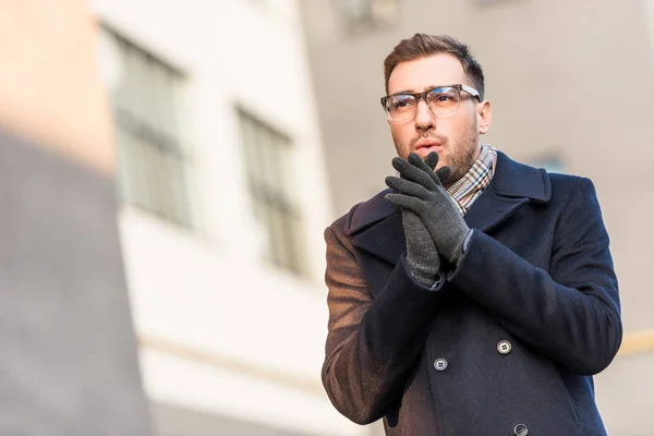 Hombre Guapo Calentando Manos Con Edificio Borroso — Foto de Stock