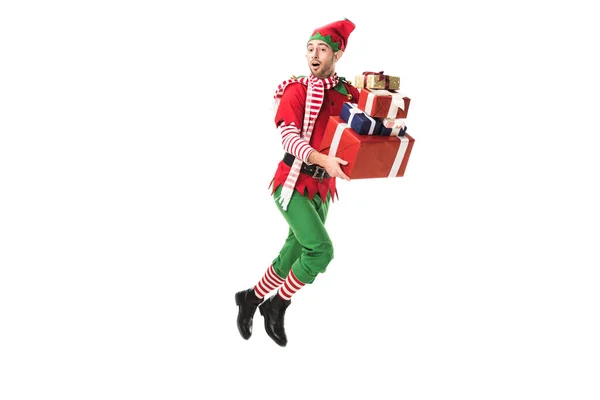 エルフの衣装はジャンプとの山を運ぶプレゼントに孤立したホワイト クリスマスで男を驚かせた — ストック写真