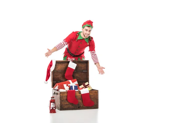 木製箱プレゼント白で隔離の近くに立っているクリスマス エルフ衣装で笑みを浮かべて男が興奮してください — ストック写真