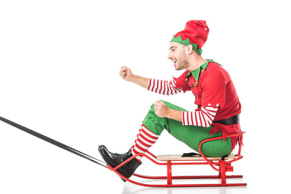 excited happy man in christmas elf costume riding sleigh isolated on white