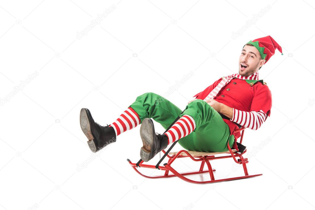 cheerful excited man in christmas elf costume riding sleigh isolated on white background