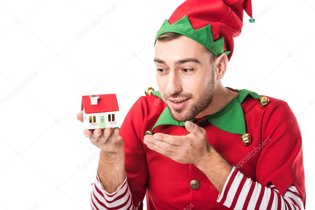 man in christmas elf costume pointing at house model isolated on white, real estate sale and insurance concept