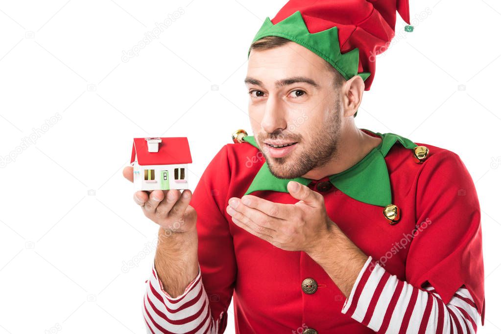 man in christmas elf costume pointing at house model isolated on white, real estate sale and insurance concept