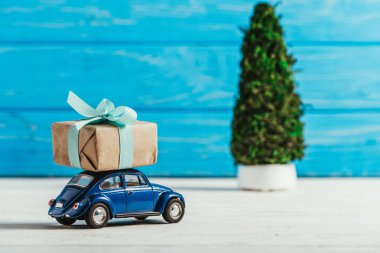 oyuncak araba mavi ahşap arka plan üzerinde hediye kutusu ve minyatür Noel ağacı ile yakın çekim çekim