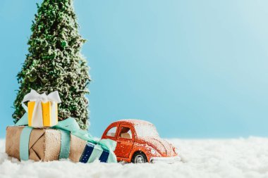 oyuncak kırmızı araba ile yakın çekim shot sunar ve kar üzerinde Noel ağacı duran mavi zemin üzerine pamuk yapılmış