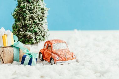 oyuncak araba ile yakın çekim shot sunar ve kar üzerinde Noel ağacı duran mavi zemin üzerine pamuk yapılmış