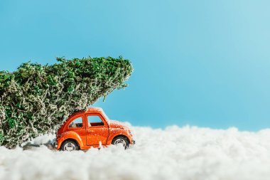 oyuncak araba minyatür Noel ağacı ile yan görünüm pamuk mavi zemin üzerine yapılan kar tarafından sürme çatı üzerinde