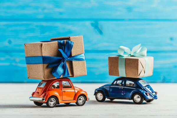 close-up shot of toy cars with gift boxes on blue wooden background
