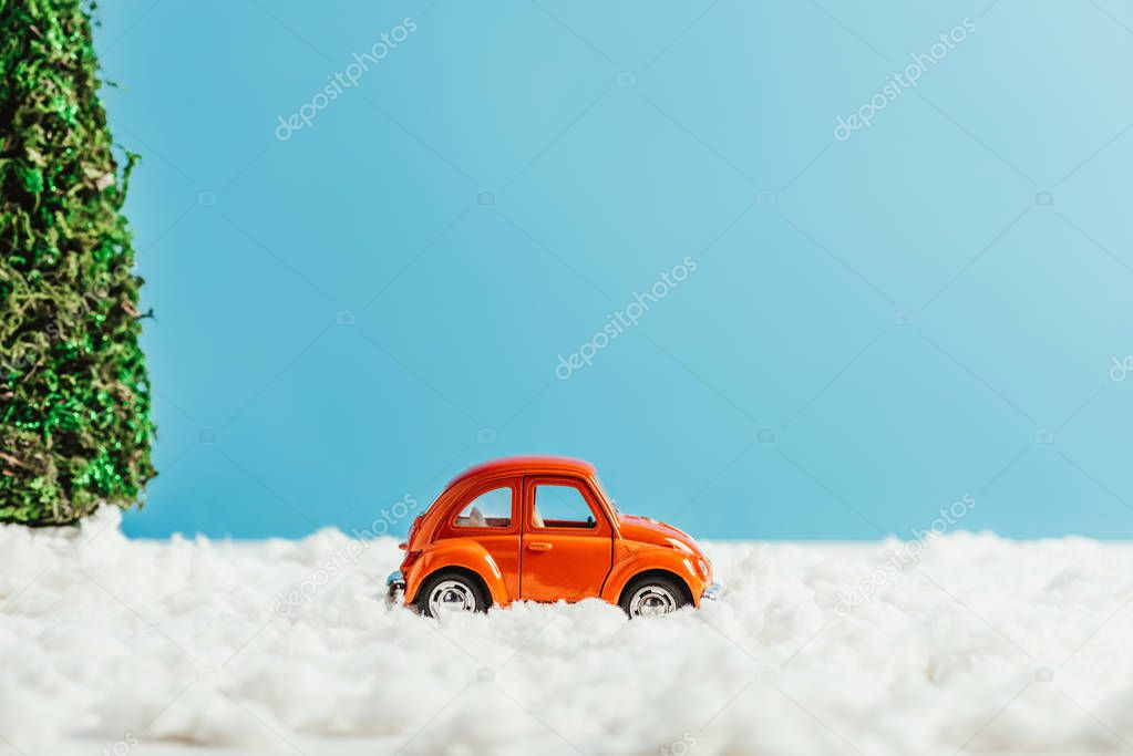 side view of toy car riding by snow made of cotton on blue background