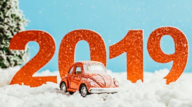 büyük kırmızı 2019 numaraları ile kar üzerinde mavi arka plan, yeni yıl kavramı üzerinde oyuncak araba duran