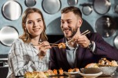 glückliches junges erwachsenes Paar isst Sushi im Restaurant