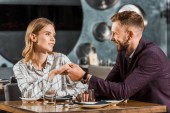 attraktives junges erwachsenes Paar hält Händchen, während es im Restaurant sitzt