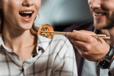 Adam kız arkadaşı suşi ile besleme kısmi görünümünü rulo