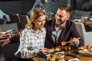 Çekici mutlu genç yetişkin çift suşi restoranında yemek