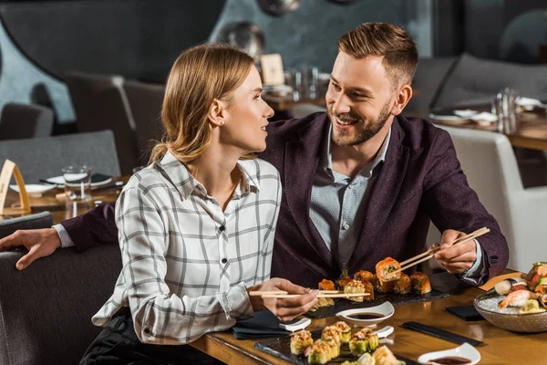 迷人的微笑的夫妇在餐厅吃饭时幽默地看着对方 — 图库照片