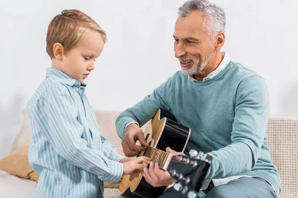 Uśmiecha Się Środku Wieku Człowiek Uczy Wnuka Gra Gitarze Akustycznej — Zdjęcie stockowe