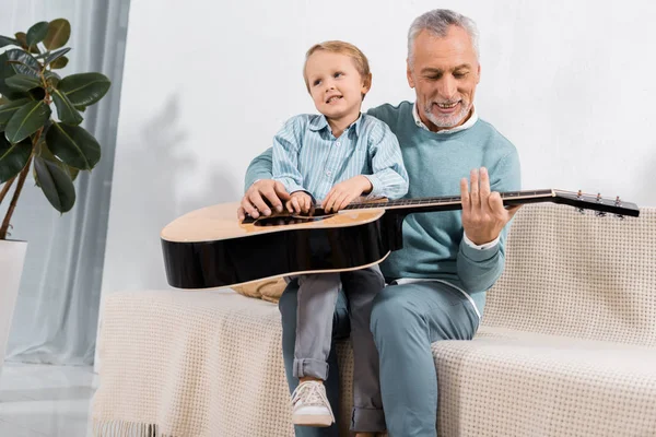 Bunicul Vesel Cântând Nepotul Genunchi Cântând Chitară Acustică Acasă — Fotografie de stoc gratuită