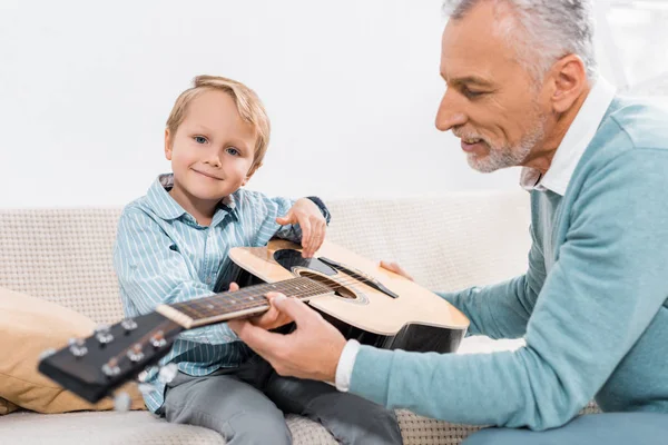 Selective Focus Middle Aged Man Teaching Grandson Playing Acoustic Guitar — Free Stock Photo