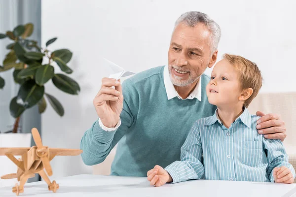 Smiling Mature Man Grandson Having Fun Paper Plane Home — Stock Photo, Image