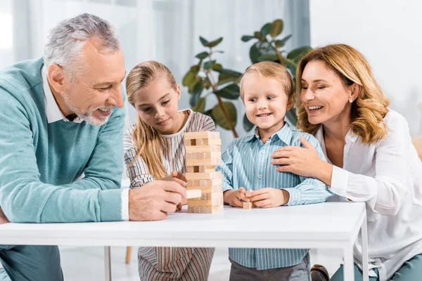 Glimlachend Grootouders Kleinkinderen Spelen Blokken Hout Tower Spel Samen Thuis — Stockfoto