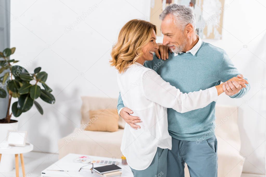 couple looking at each other while dancing in living room at home