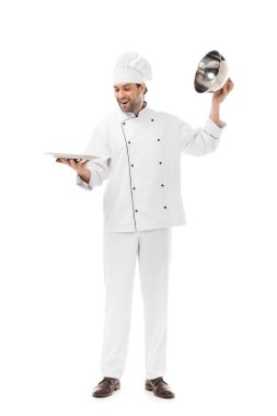 happy young chef taking of serving dome from plate isolated on white clipart
