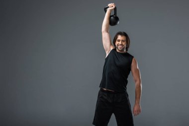 Kettlebell ile eğitim ve gri izole kamera gülümseyen kas genç adam