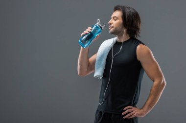 havlu içme suyu gri izole spor şişe ile gülümseyen kaslı adam