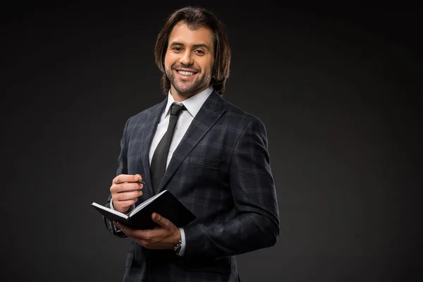 Joven Empresario Profesional Escribiendo Bloc Notas Sonriendo Cámara Aislada Negro — Foto de stock gratis