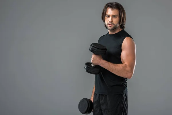 Jovem Musculoso Exercitando Com Halteres Olhando Para Câmera Isolada Cinza — Fotografia de Stock