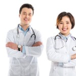 Sonrientes médicos femeninos y masculinos mirando a la cámara con los brazos cruzados aislados en blanco
