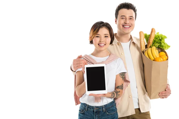 Sonriente Marido Sosteniendo Bolsa Comestibles Mientras Esposa Presentando Tableta Digital — Foto de Stock