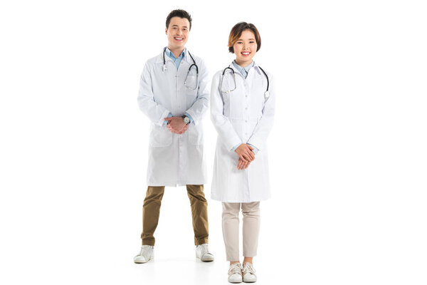 female and male doctors with folded hands looking at camera isolated on white