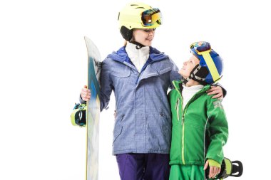 Snowboard üzerinde beyaz izole snowsuit sarılma varoluş oğlu ile yetişkin anne gülümseyerek