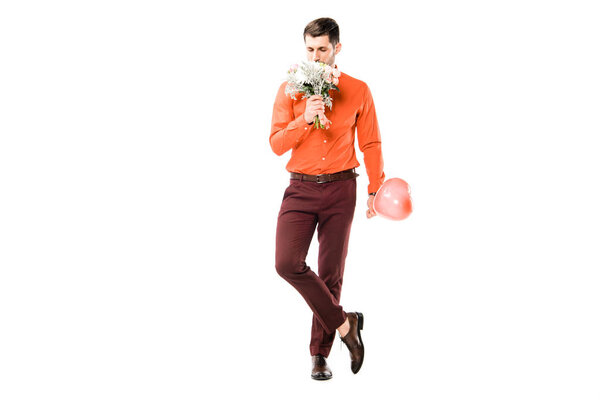 Handsome man smelling bouquet of flowers while holding red baloon isolated on white
