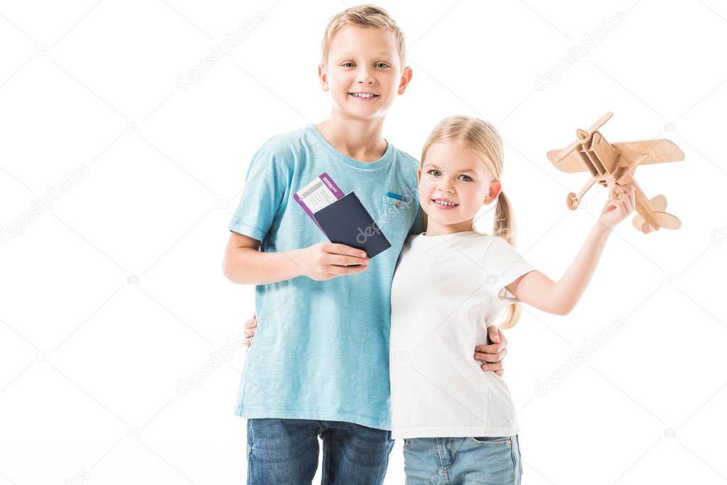 Kids standing with plane model, passport and tickets isolated on white