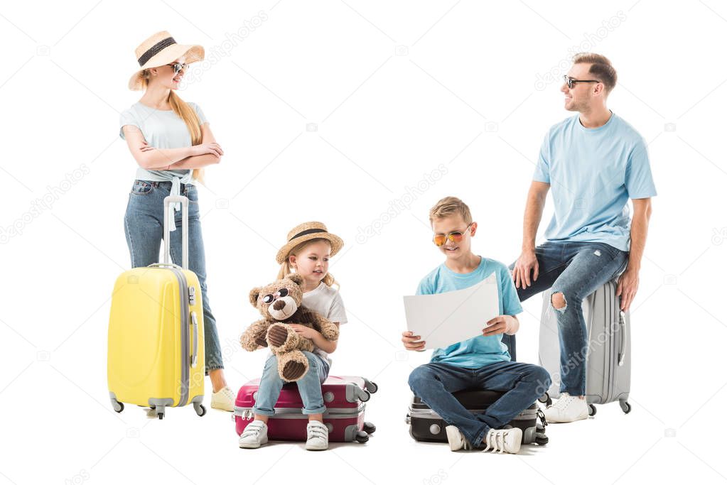 Family sitting on luggage and looking at map isolated on white