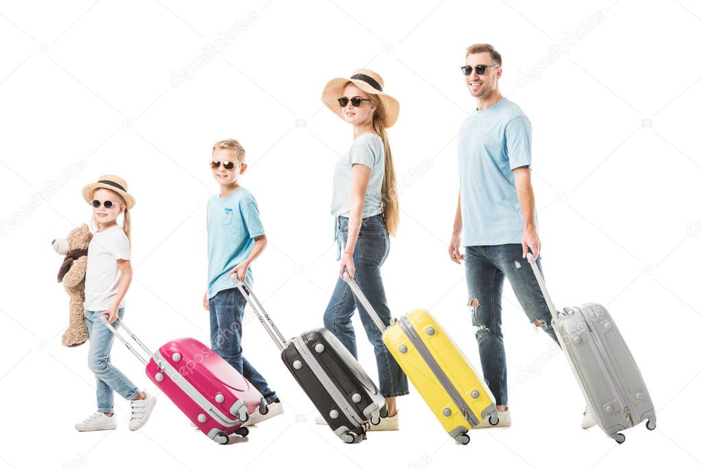 Happy family walking with colourful luggage and smiling isolated on white