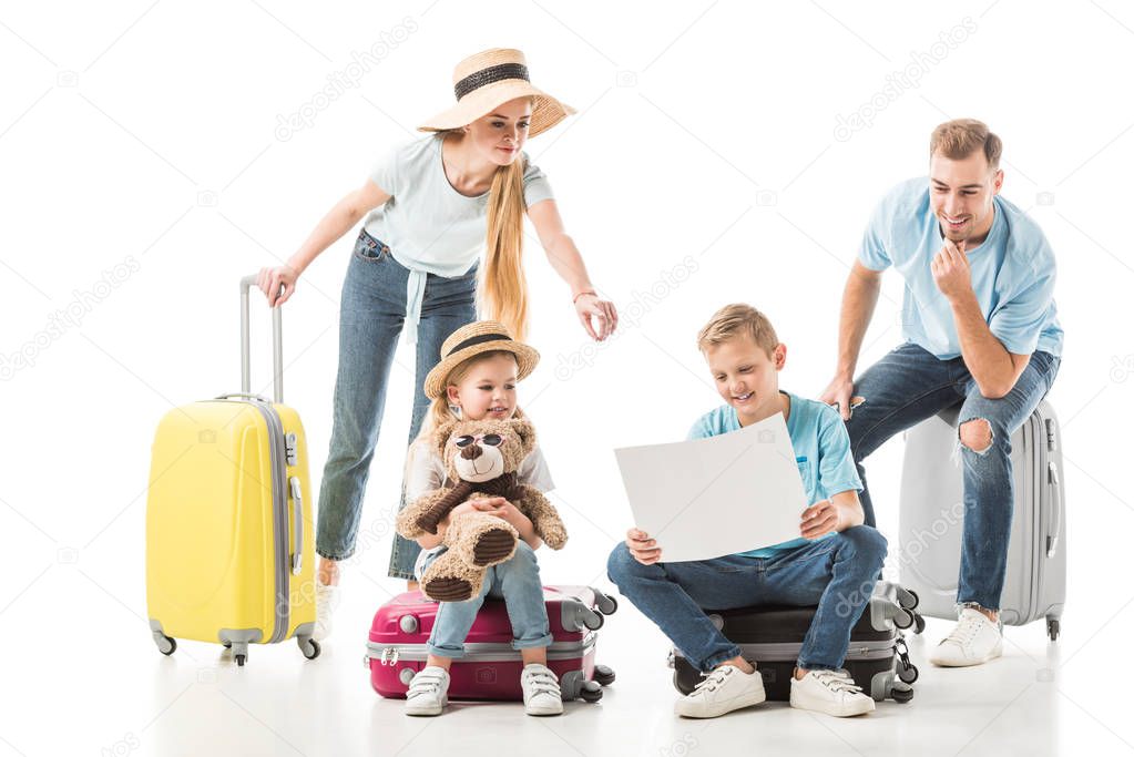 Mother pointing at map and kids with dad sitting on luggage isolated on white