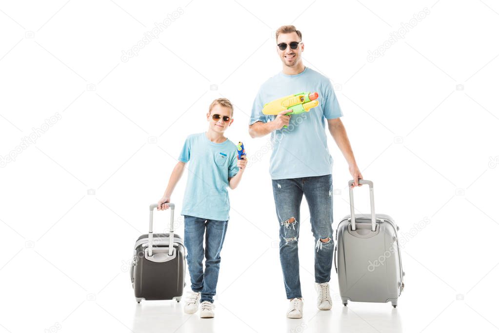 Dad and son walking with luggage and holding water guns isolated on white