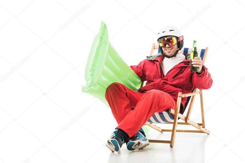 man in ski clothes with beer bottle and pool mattress sitting in deck chair and smiling isolated on white