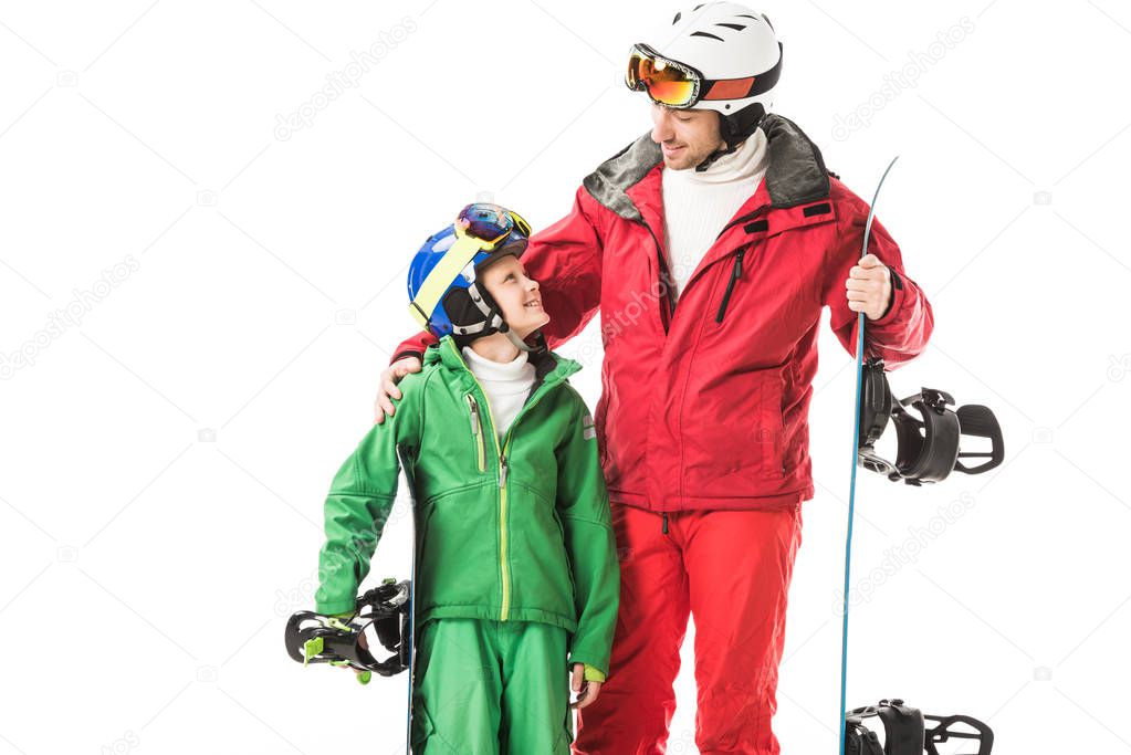 adult father in ski suit embracing preteen son with snowboard isolated on white
